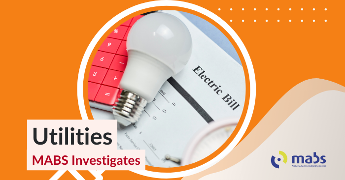 Blog banner image with a magnifying glass that holds an image of a light bulb on top of an electricity bill. Text below reads "Utilities - MABS Investigates"