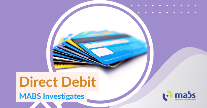 Blog banner image with a magnifying glass that holds an image of debit cards stacked. Text below reads "Direct Debit - MABS Investigates"