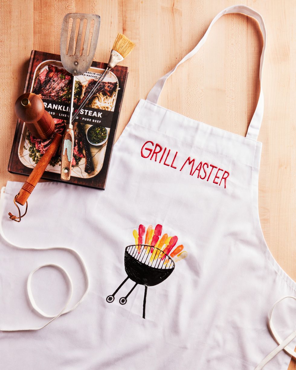 A white Apron with Grill Master written on the front and a drawing of a barbecue underneath Grill Master 