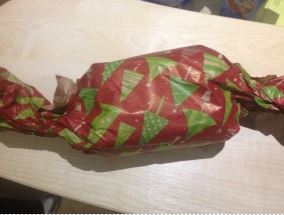 Homemade Enrichment box in red gift wrapping with green Christmas tree pattern on it